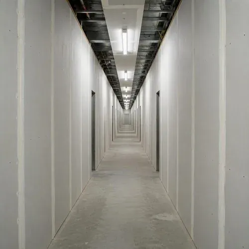 Drywall panels installed along a long commercial corridor, joints staggered for a flat finish