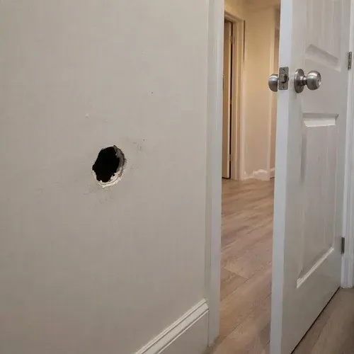 Doorknob punched clean through hallway drywall, the most common repair call we take