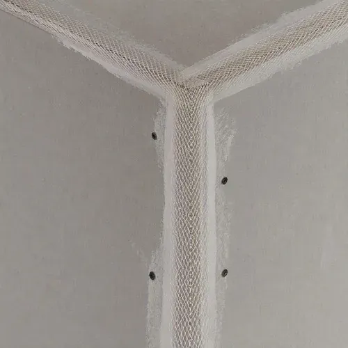 Mesh tape covering an inside corner joint before the corner is coated and struck