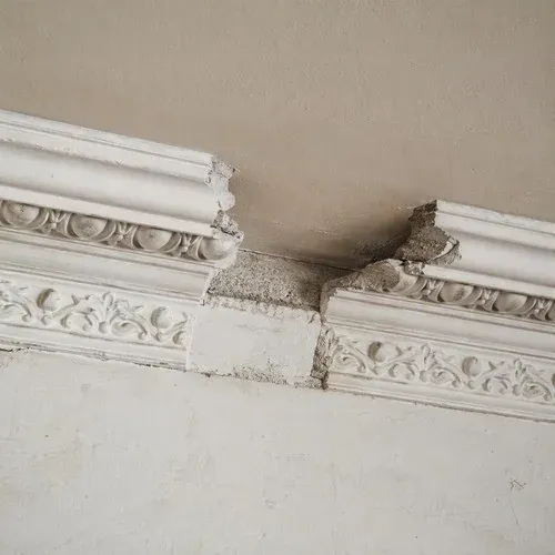 Damaged plaster crown moulding with a decorative section missing entirely