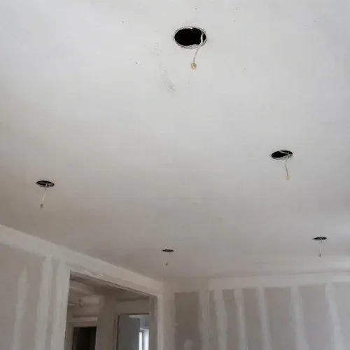 Several open recessed light holes across a ceiling after a lighting layout was changed