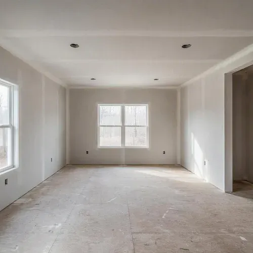 Finished smooth drywall walls in an empty living room, sanded to a Level 4 paint-ready surface