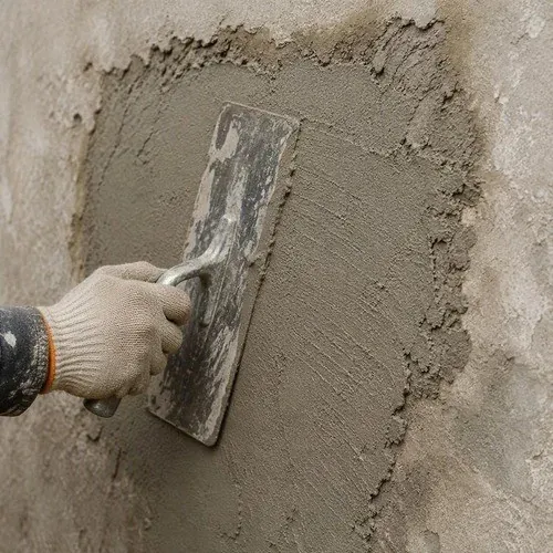 Hand troweling fresh stucco onto a patched wall section, built up in coats