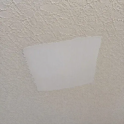 Knockdown textured ceiling with a damaged area patched flat and waiting for texture