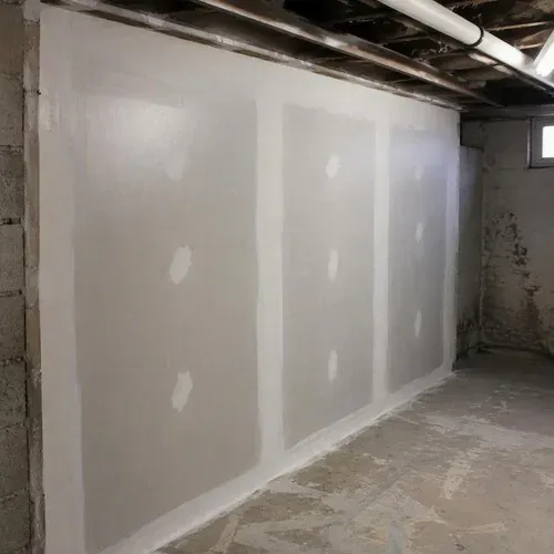 New moisture-resistant drywall replacing a water damaged basement wall, taped and finished